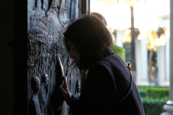 Piligrimas paliečia Šv. Pauliaus už sienų bazilikos Šventąsias duris / EPA nuotr.